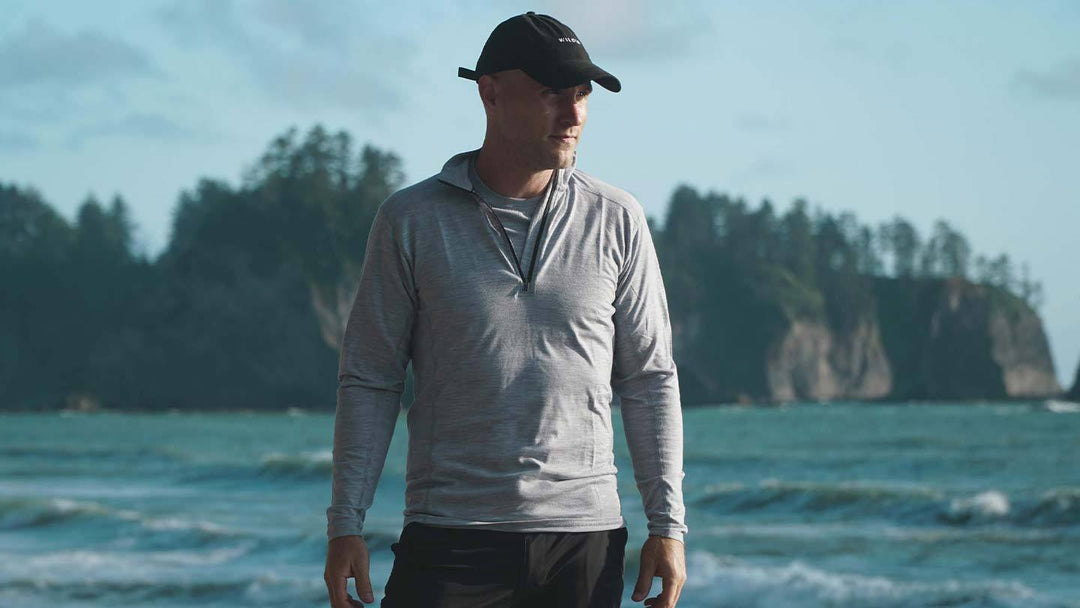 man next to ocean wearing minus33 merino wool micro 1/4 zip base layer shirt