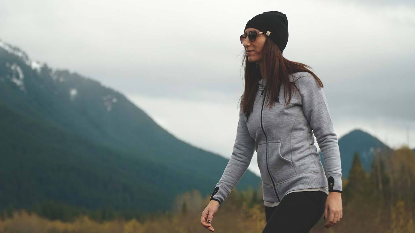 woman hiking in front of mountain while wearing minus33 merino wool expedition hoodie sweatshirt and beanie