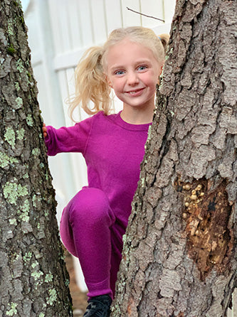 girl climbing a tree in midweight base layer