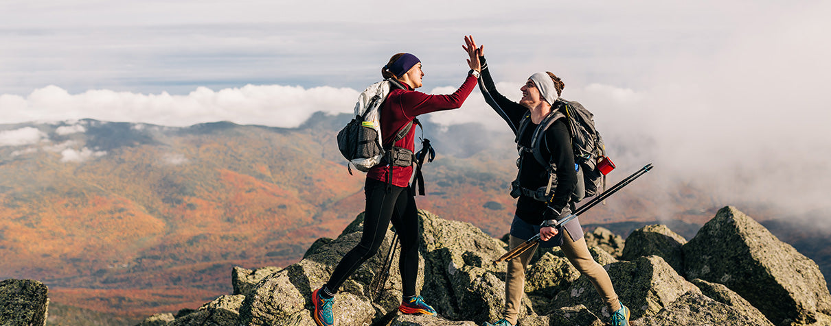 people high fiving on top of a mountain wearing midweight merino wool