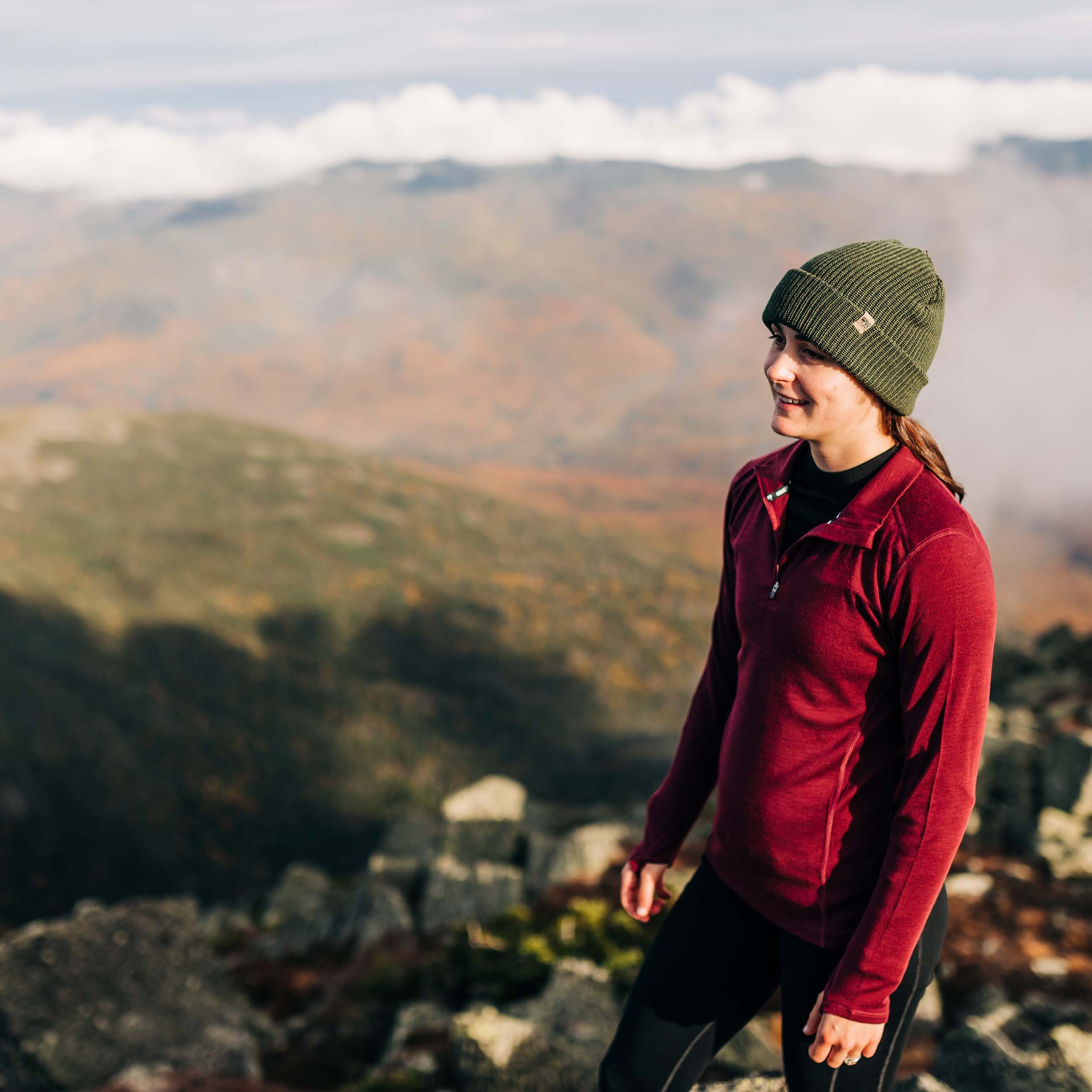 woman hiking wearing a beanie and midweight 100 percent merino wool maroon quarter zip in the fall