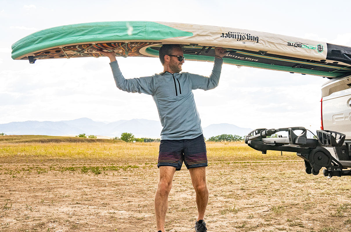 man at the lake loading up with paddleboard while wearing a micro weight merino wool quarterzip