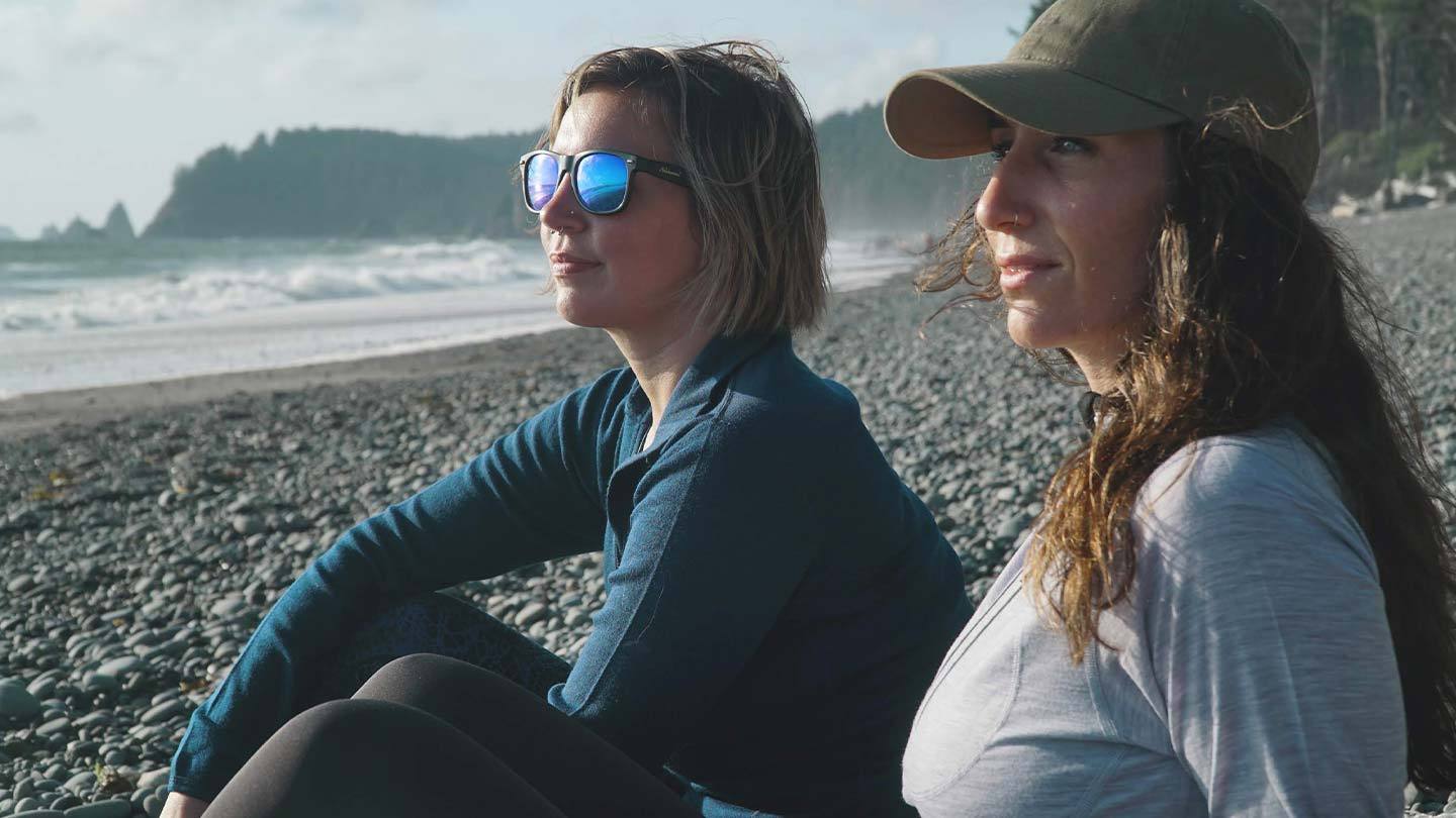 two women sitting on beach wearing minus33 merino wool new base layer shirts
