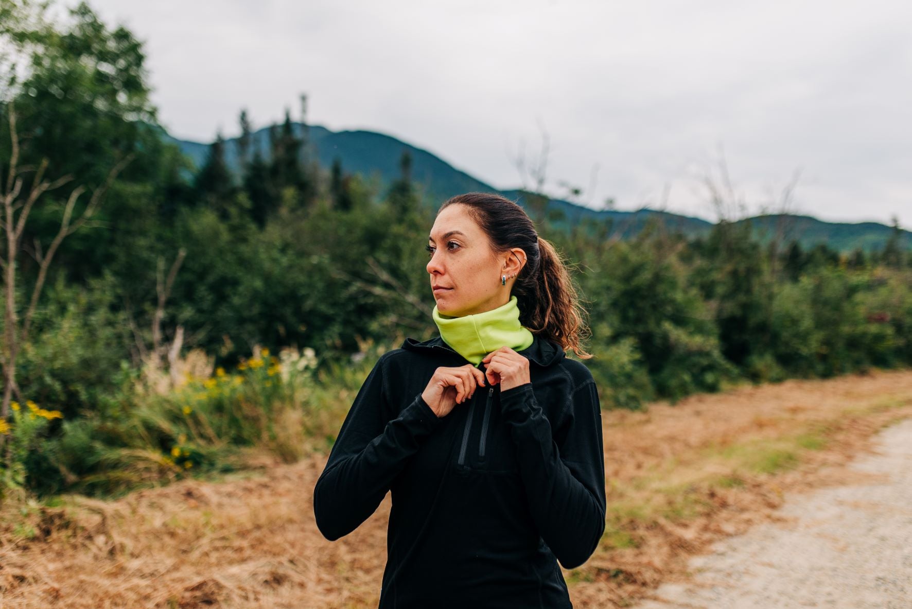 Woman in a black Micro weight, zip up Hoodie, on a trail 