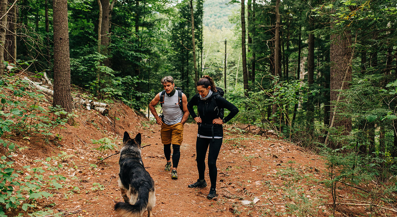 couple hiking with their dog wearing micro weight merino wool