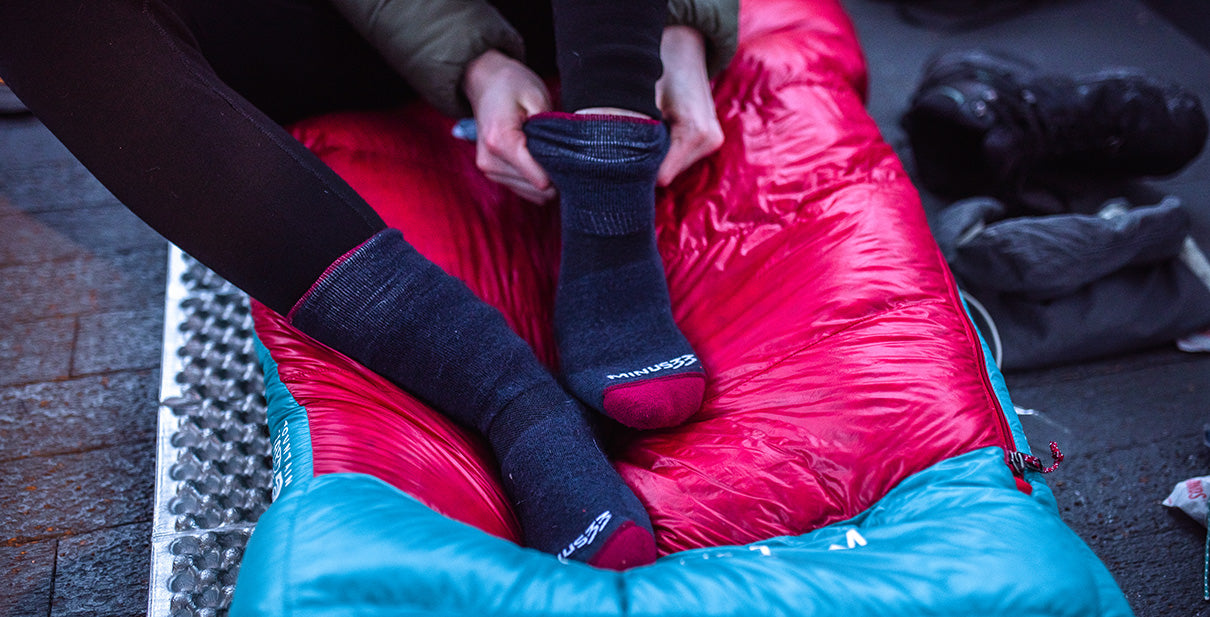person pulling up their socks while camping in the winter