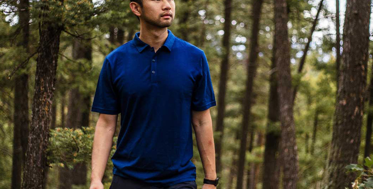 man walking in the woods wearing a lightweight navy blue polo