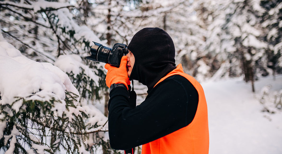 man taking winter photos wearing expedition base layers