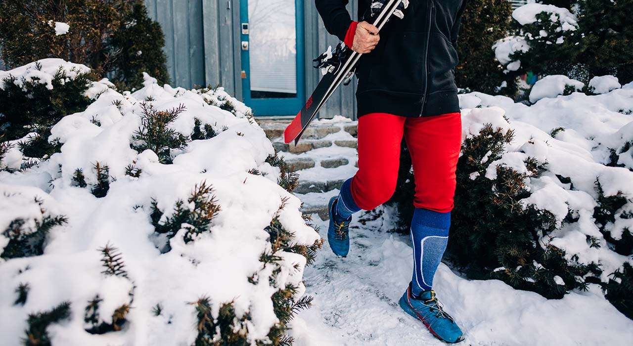man walking with skis wearing mid weight true red base layer bottoms