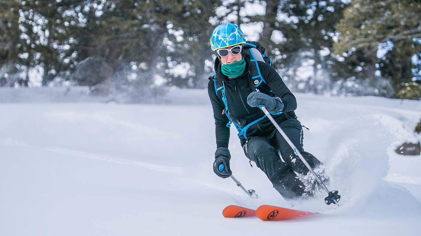 woman skiing while wearing minus33 merino wool expedition sweatshirt hoodie and neck gaiter