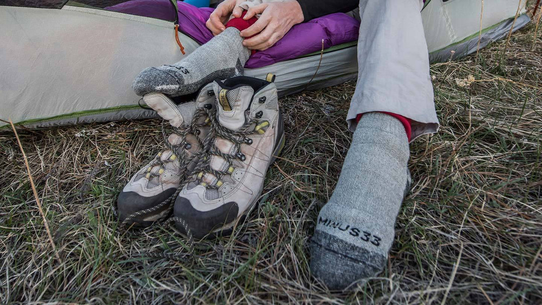 closeup of woman putting on minus33 merino wool expedition socks in tent