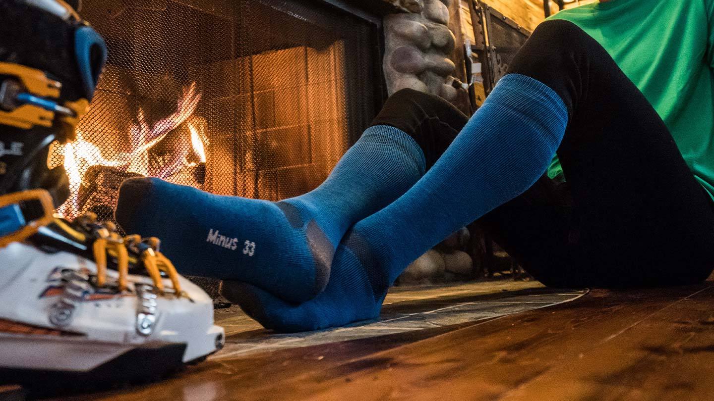 man sitting by fireplace wearing minus33 merino wool ski and snowboard lightweight socks