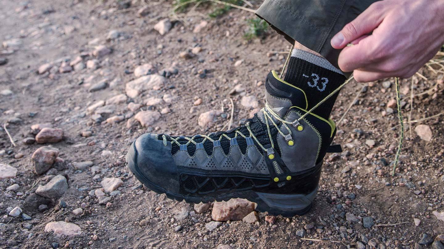 closeup of man lacing up hiking boots while wearing minus33 merino wool lightweight low cut socks