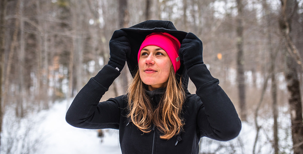 woman hiking wearing black expedition kodiak fleece hoodie and blaze pink ridge cuff beanie in the winter