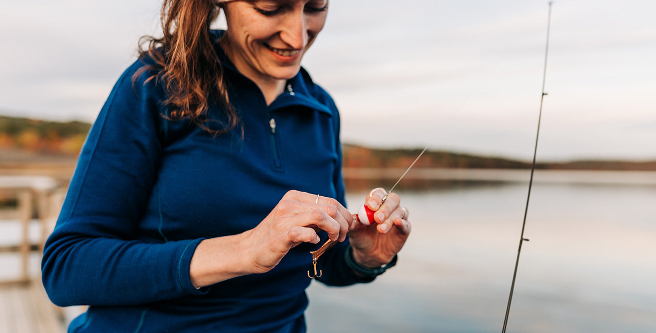 woman fishing with a midweight 1/4zip 100% merino wool navy blue