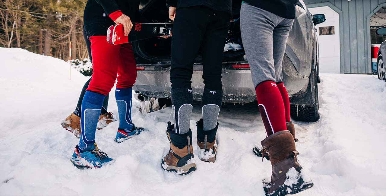 group of people getting ready to go skiing wearing base layer bottoms and ski and snowboard socks