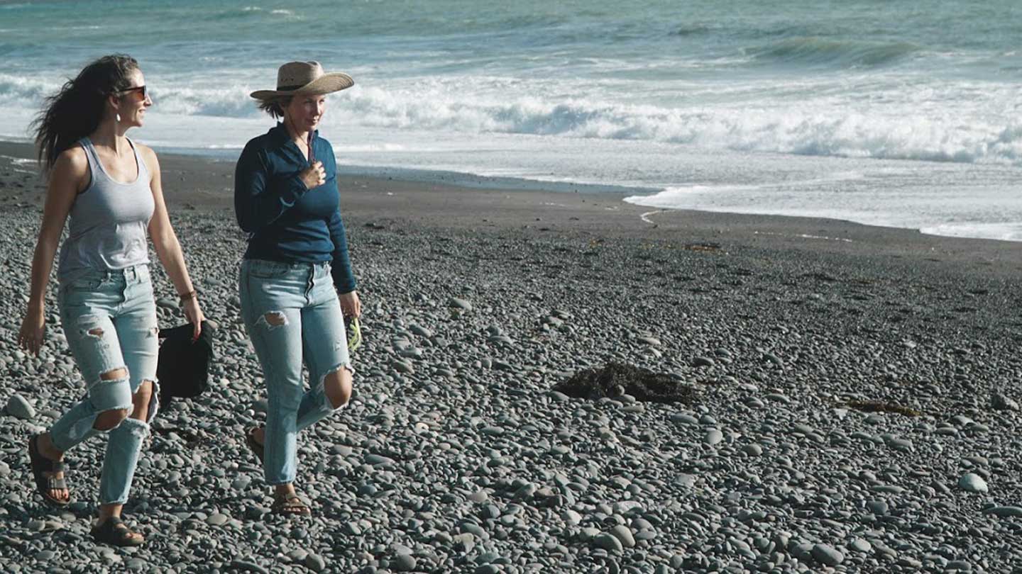 two women walking on the beach wearing merino wool tank top and base layer
