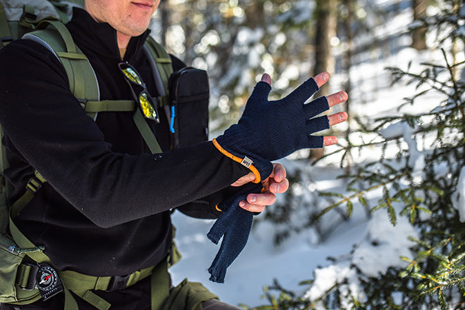 man putting on fingerless gloves while winter hiking