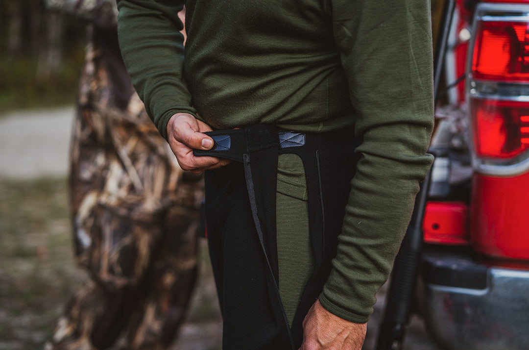 man zipping up merino wool mid layer bottoms for hunting