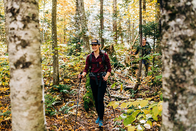 woman hiking in the woods wearing midweight burgundy 1/4 zip