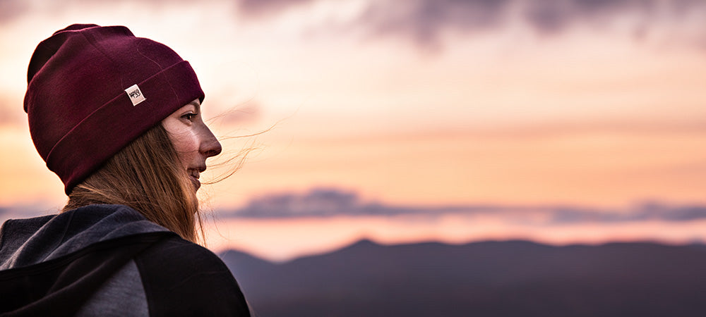 woman looking over mountains wearing a midweight ridge cuff beanie and a midweight woolverino zip up hoodie
