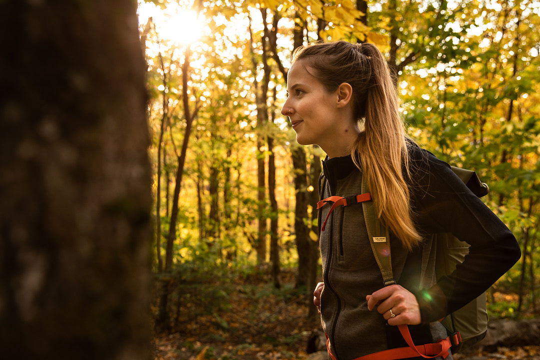 woman hiking in the woods during the fall wearing the midweight woolverino full zip hoodie